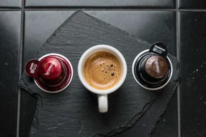 Capsules compatibles Nespresso pour espresso serré alignées sur une ardoise noire avec une tasse d'espresso au centre