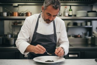 Chef français en blanc sert du caviar sur une assiette