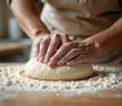 Mains de boulanger pétrissant la pâte sur un plan de travail en bois
